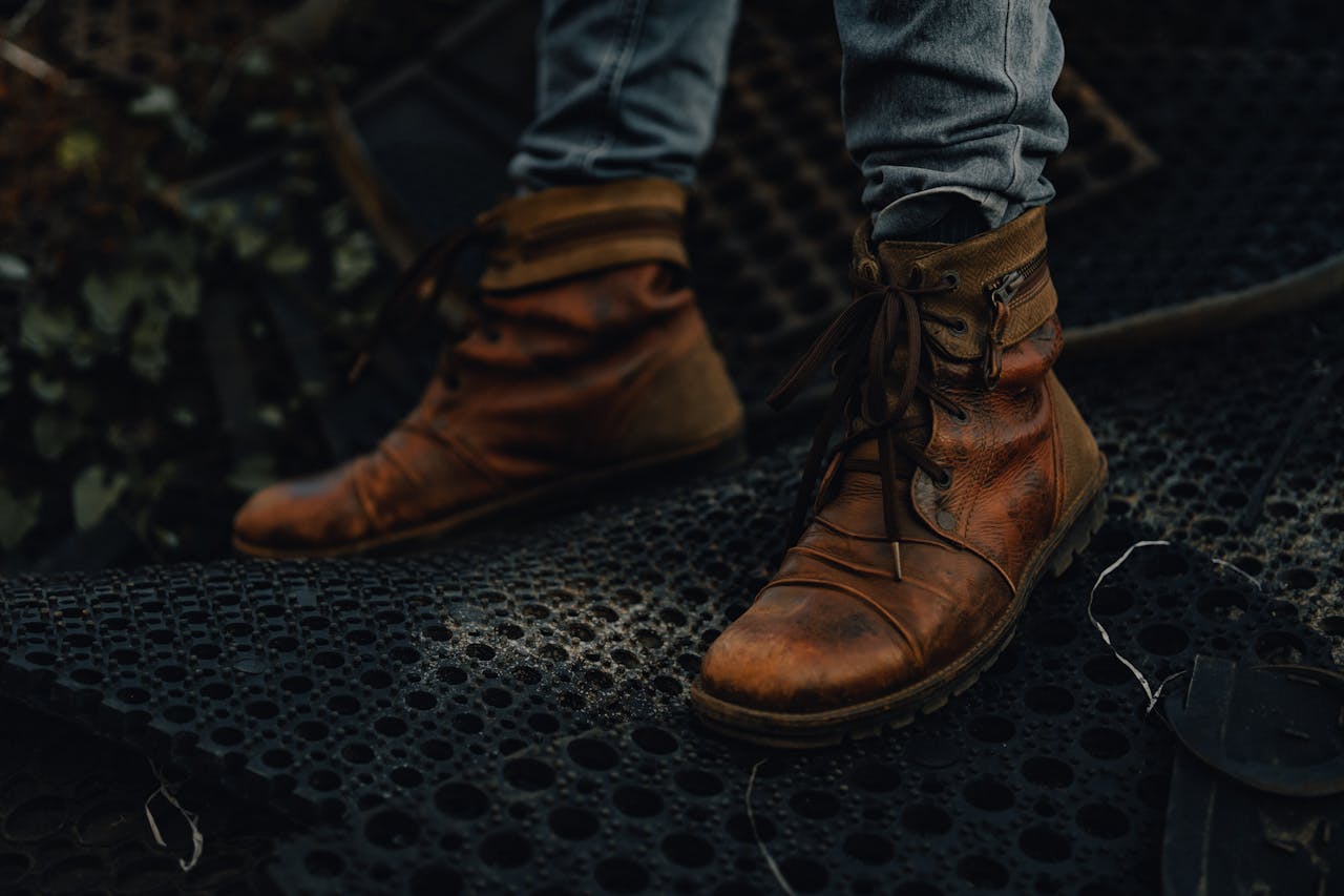 Close-up of brown leather boots on a textured dark surface. Urban and rugged feel.