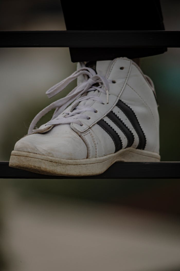 Detailed close-up of white sneakers with black stripes on a railing, Sri Lanka.